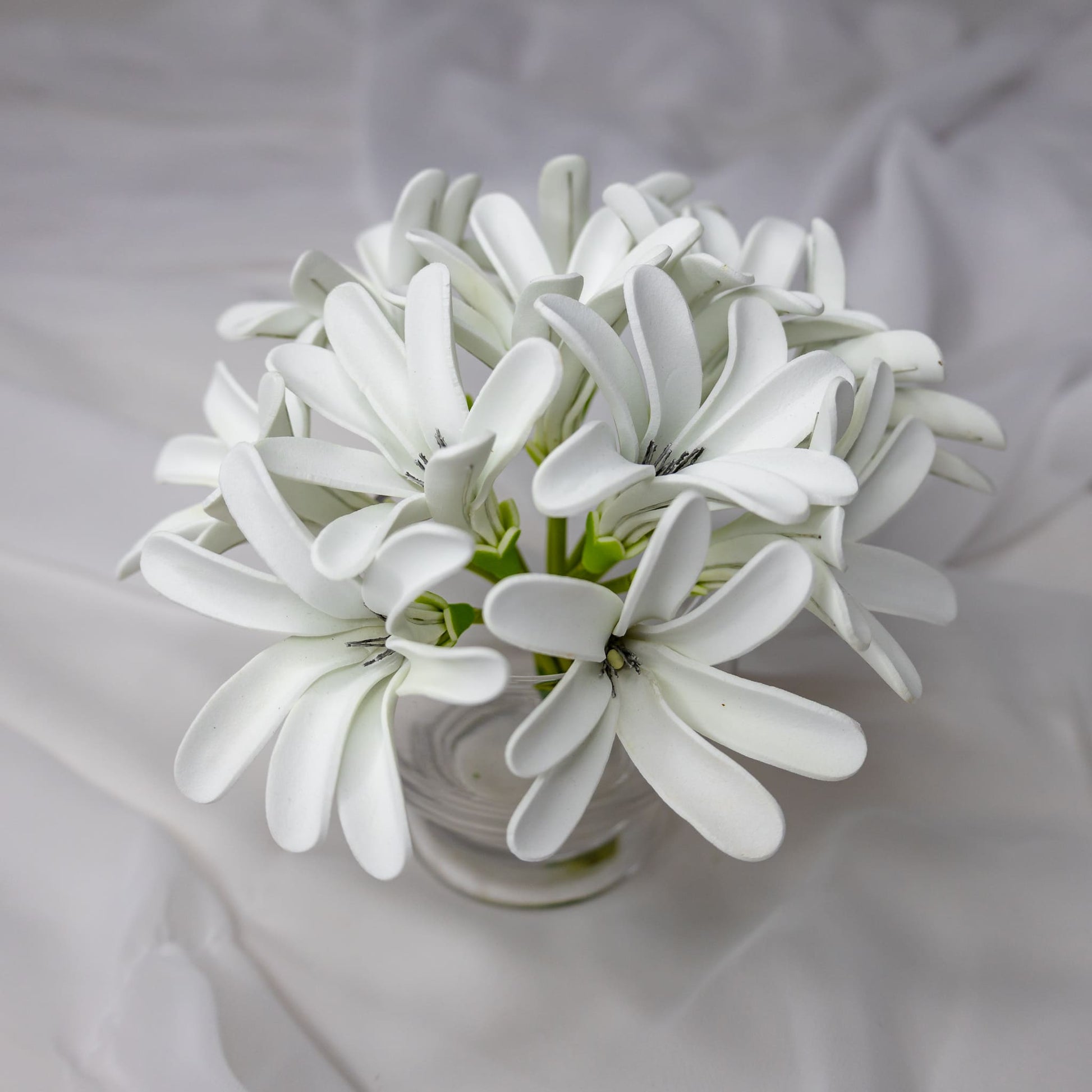 artificial tahitian gardenia flowers placed in transparent glass vase