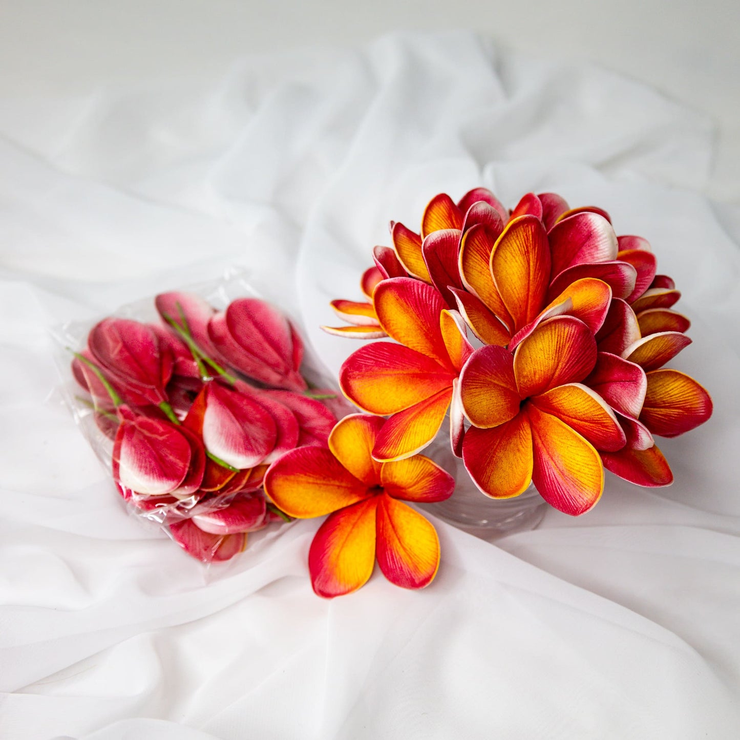 artificial tropical frangipani flowers placed in transparent glass vase