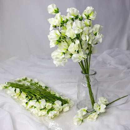 artificial white sweet pea placed in transparent glass vase