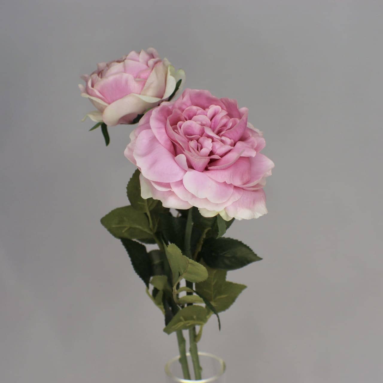 artificial half bloom pink ice roses placed in transparent glass vase