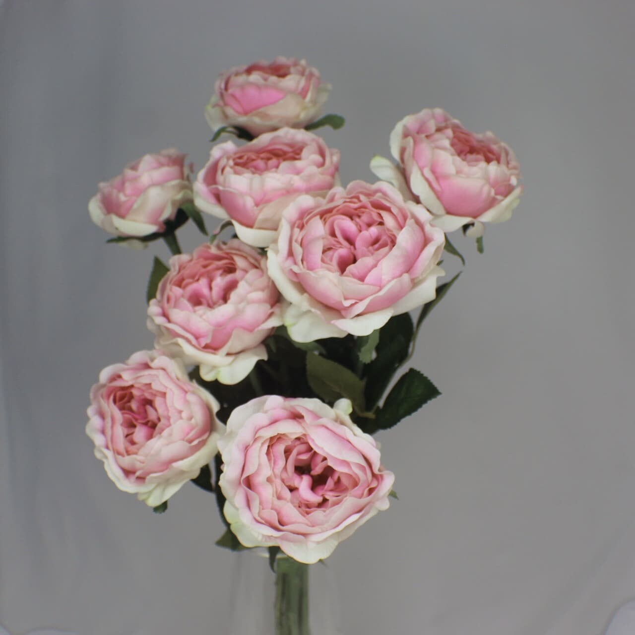 artificial half bloom pink ice roses placed in transparent glass vase