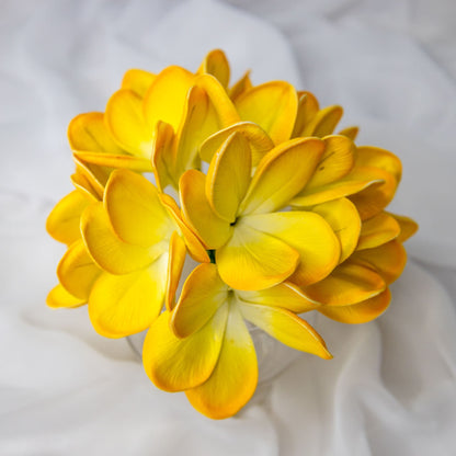 artificial tahitian gold frangipani flowers placed in transparent glass vase