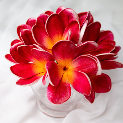 artificial passion frangipani flowers placed in transparent glass vase