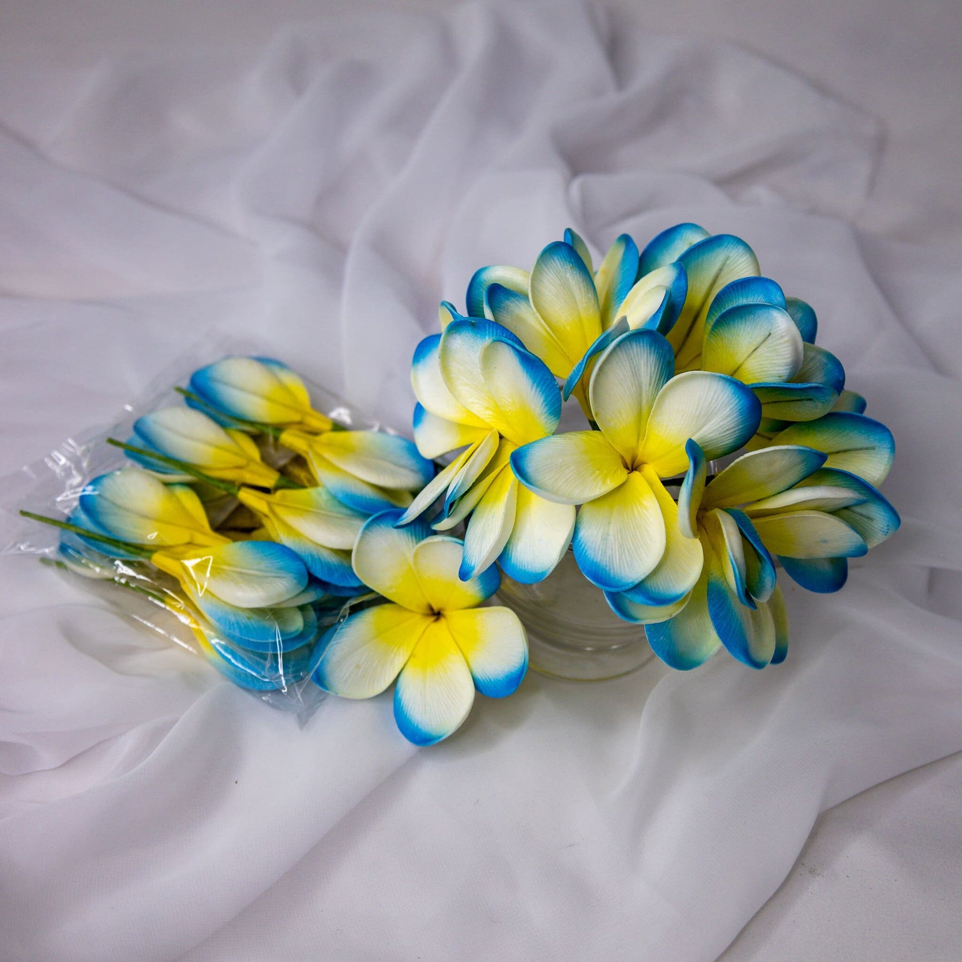 artificial skye blue frangipani flowers placed in transparent glass vase