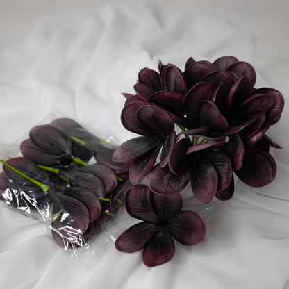 artificial midnight frangipani flowers placed in glass vase