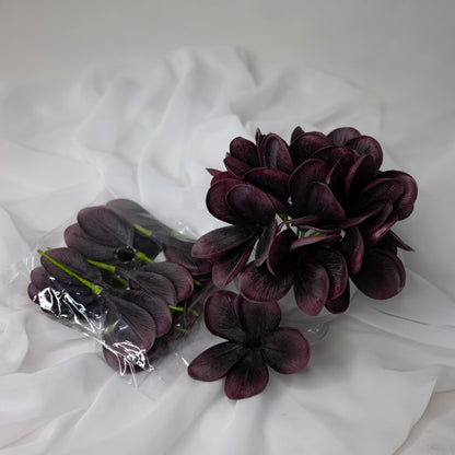 artificial midnight frangipani flowers placed in glass vase