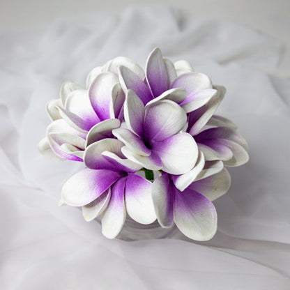 artificial picasso frangipani flowers placed in transparent glass vase