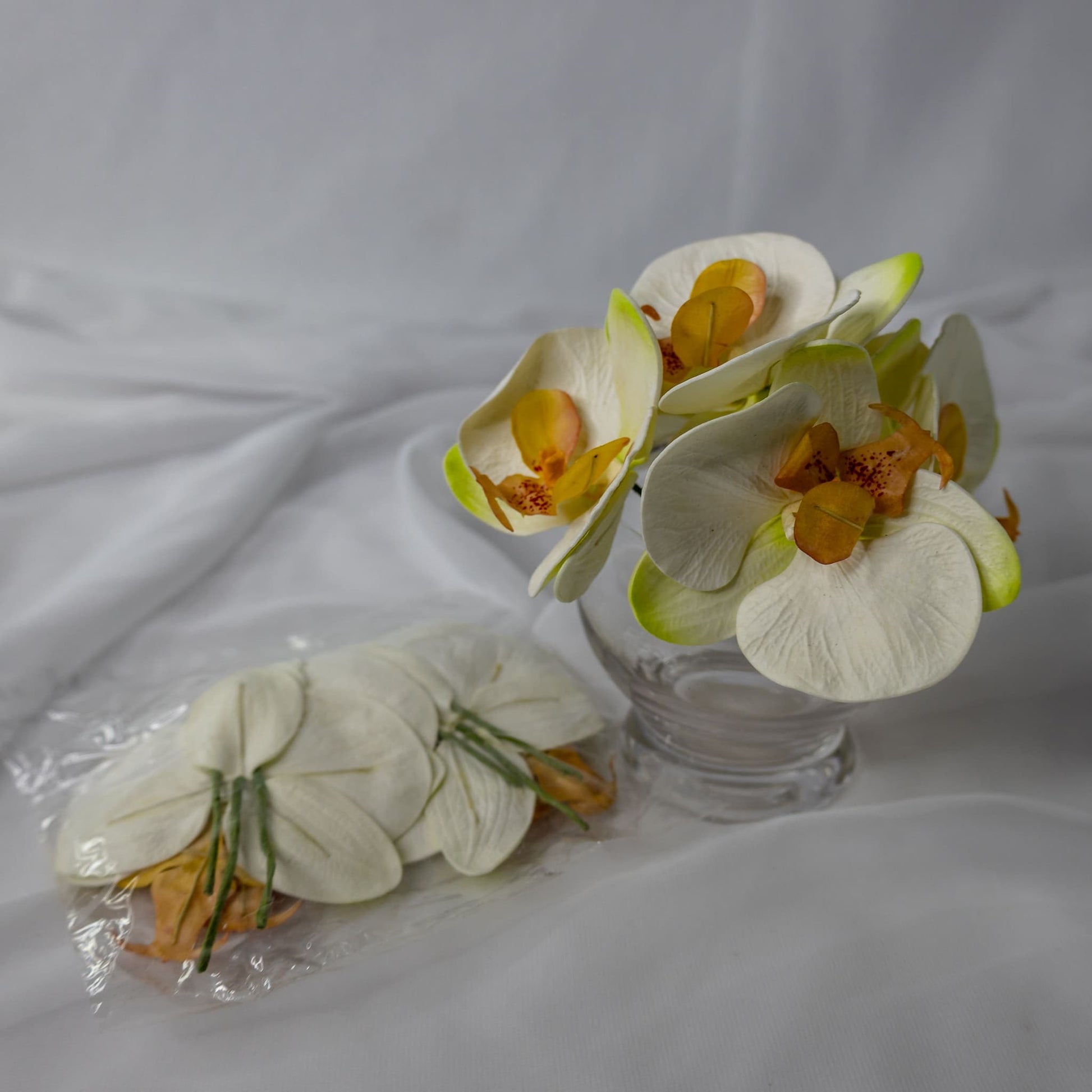 artificial Phalaenopsis flowerheads placed in transparent glass vase