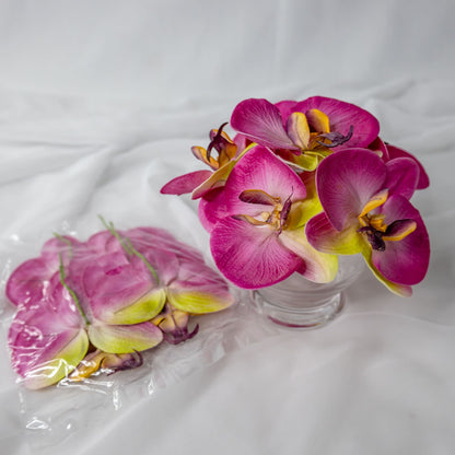 artificial purple pink phalaenopsis flowers placed in transparent glass vase