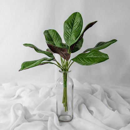 artificial small magnolia leaves placed in transparent glass vase