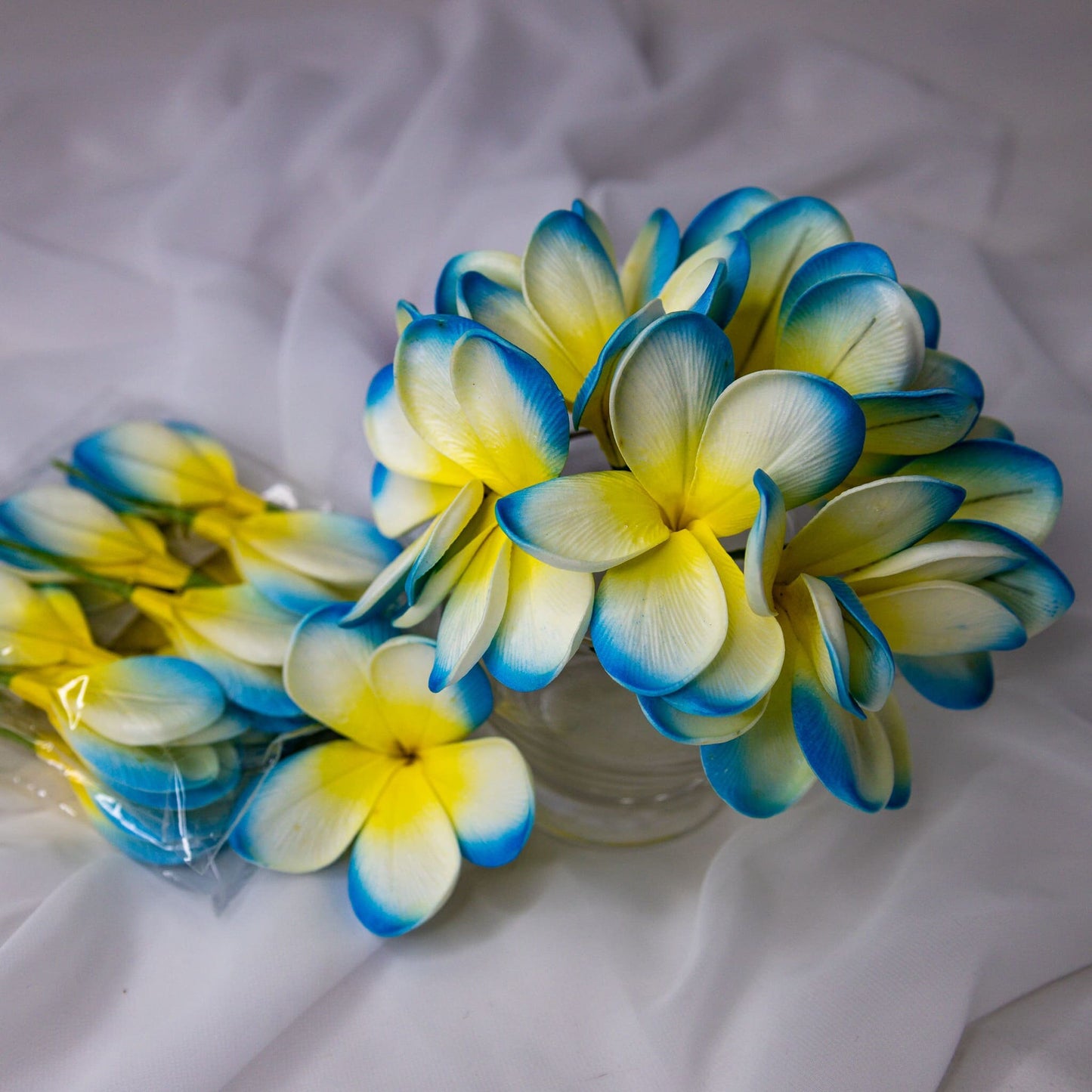 artificial skye blue frangipani flowers placed in transparent glass vase