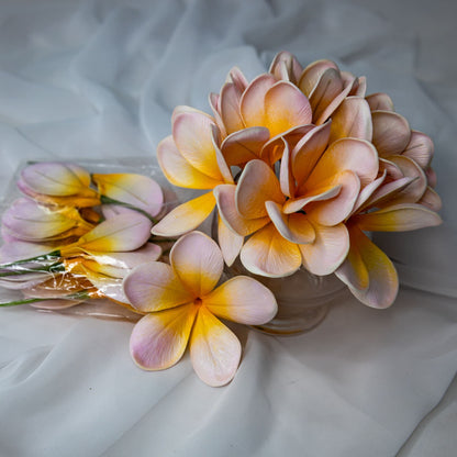 artificial pale frangipani flowers place in transparent glass vase