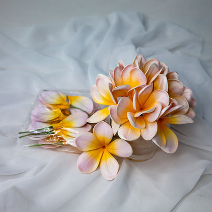 artificial pale frangipani flowers place in transparent glass vase