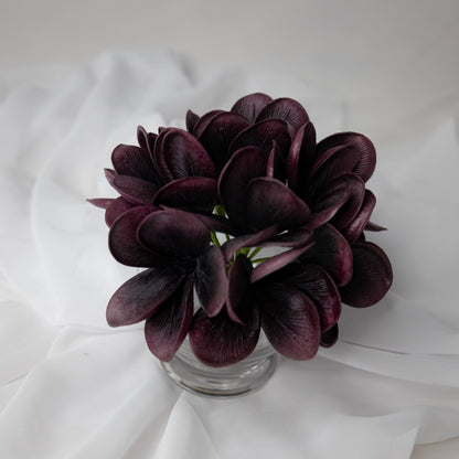 artificial midnight frangipani flowers placed in glass vase